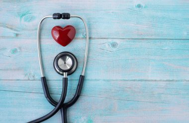 Ahşap masa mavisi arka planda kontrol için doktor kırmızı kalbi olan siyah stetoskop. Stetoskop ekipmanları ses tanısı koymak için kullanılır. Fotokopi alanına sahip sağlık ve kardiyoloji kavramı.