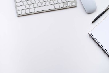 Beyaz ofis masasının üstünde klavye, defter ve kalemle diğer ofis malzemeleri. İş ve finans kavramı. Çalışma yeri, boş kopya alanı olan düz uzanma.