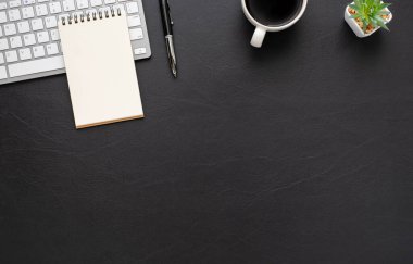 Klavyeli siyah ofis masası, not defteri ve ekipman ofis malzemeleriyle dolu kahve fincanı. İş ve finans kavramı. İş yeri, Üst Görünüm dairesi boş kopya alanı ile yatıyordu.