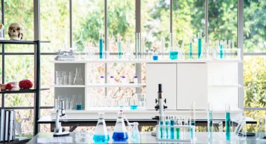 Cam eşyalar, beyaz masada mavi sıvı içeren tüp gibi laboratuvar ekipmanlarının hazırlanması. Bilimsel araştırmalarda kimya deneyi