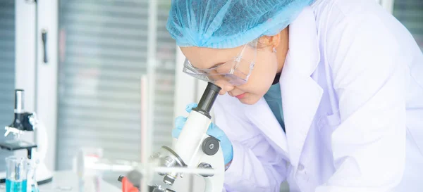 Asya kadın bilim adamı, araştırmacı, teknisyen veya öğrenci tıbbi, Kimya veya biyoloji laboratuarında Bilimsel ekipman olan mikroskop kullanarak araştırma veya deney yaptı