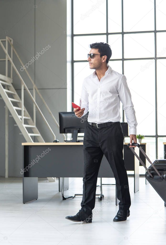 Young and smart businessman with sunglasses, suitcase and travel document such as air ticket, hotel booking document and passport with travel concept,summer vacation concept, summer holiday concept
