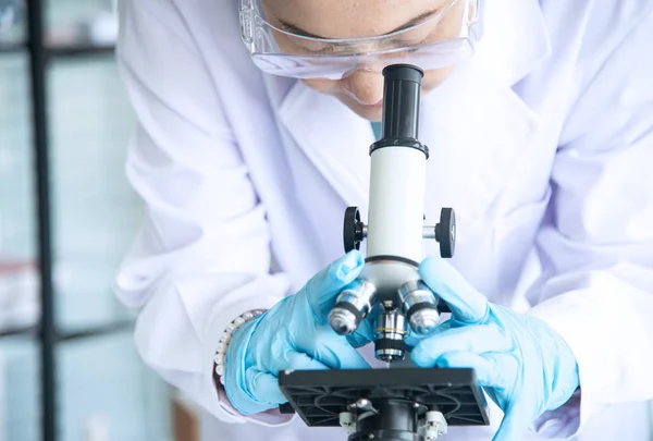 Femeie de știință asiatică, cercetător, tehnician sau student a efectuat cercetări sau experimente prin utilizarea microscopului care este echipament științific în laboratorul medical, chimie sau biologie — Fotografie, imagine de stoc