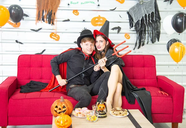 Happy Halloween party concept. Young man and woman wearing the fantacy as vampires, witch or ghost celebrate the halloween festival in the room decorated with balloon, bat and pumpkin.