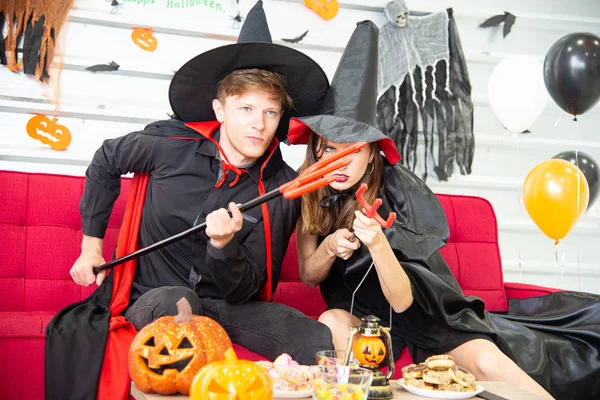 Feliz concepto de fiesta de Halloween. Joven hombre y mujer vistiendo la fantasía como vampiros, brujas o fantasmas celebran el festival de Halloween en la habitación decorada con globo, murciélago y calabaza . — Foto de Stock