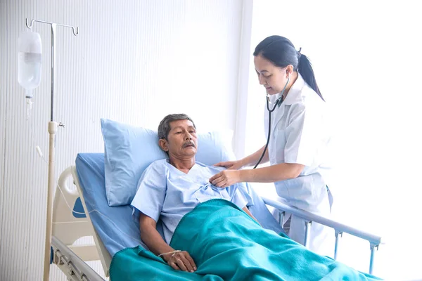 Asiatische Ärztin mit Notizblock lächelnd Besuch sprechen und diagnostizieren den alten Mann Patient im Krankenbett auf der Krankenstation — Stockfoto