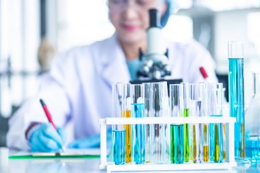 Asyalı kadın bilim adamı cam gibi Laboratuvar ekipmanları hazırlanıyor, beyaz masada mavi sıvı ile tüp. Bilimsel araştırmalarda kimya deneyi