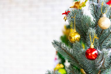 Noel ve yeni yıl tatili konsepti. Beyaz tuğla duvar ve bokeh üzerinde kurdele topları ve süsler ile yakın ve bulanık Noel ağacı süsleme