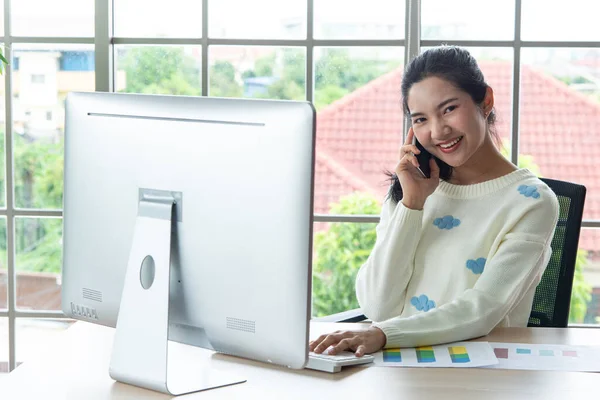 Evden ve internetten öğrenme konseptinden çalış. Bilgisayarda çalışan güzel genç kadınlar oturma odasındaki akıllı telefonu ya da çalışma alanını kullanarak ekrana bakarlar. Öğrenci çevrimiçi eğitim kursu.