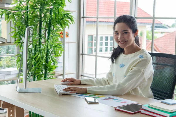 Work from home and online learning concept. Pretty young women working on computer look at the screen in the living room or co-working space. Student study online training course.