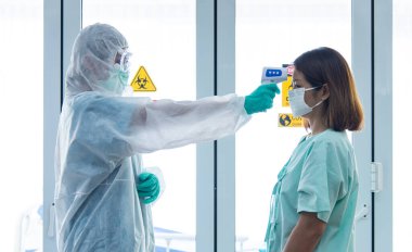 COVID-19, Corona Virüsü salgını karantina ve salgın yayılma konsepti. Asyalı doktorlar hastanede karantina odasında hasta sıcaklığını ölçmek için PPE eldiveni ve yüz maskesi takıyorlar.