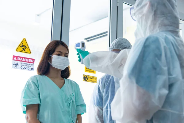 COVID-19, Corona Virüsü salgını karantina ve salgın yayılma konsepti. Görünmez Asyalı doktorlar hastane karantina odasındaki hasta sıcaklığını ölçmek için PPE eldiveni ve yüz maskesi takıyorlar.