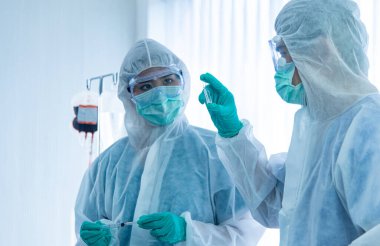 COVID-19, Corona Virüsü salgını karantina salgını yayılması ve sosyal uzaklık kavramı. Asyalı doktorlar PPE izleme cihazı takıyor ve CORONA veya COVID-19 hasta enfeksiyonu tedavisine başvuruyor