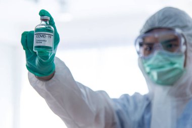 COVID-19, Corona Virüs aşısı araştırma ve geliştirme konsepti. Bulanık Asyalı doktor COVID-19 aşısı gösteriyor.