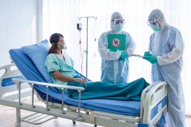 COVID-19, Corona Virüsü salgını karantina salgını sosyal uzaklık kavramını yaydı. Asyalı doktorlar, CORONAVIRUS veya COVID-19 hasta tedavi dosyalarını gösteren PPE eldiven ve yüz maskesi takıyorlar..