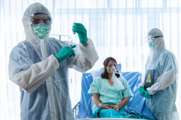 Koruyucu kıyafetli bulanık doktorlar hastanedeki karantina odasında CORONA VISRUS veya COVID-19 ile enfekte olan hastayı izliyor ve enjekte ediyor..