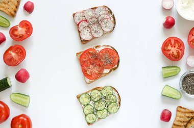 Krem peynir, taze salatalık, turp, domates, beyaz arka plan üzerinde chia tohum ile sandviçler. Genel gider Gıda çekim. Düz yatıyordu