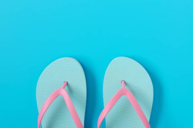 Mavi arka plan üzerinde parmak arası terlik. Yaz konsepti. Kopyalama alanı kompozisyon