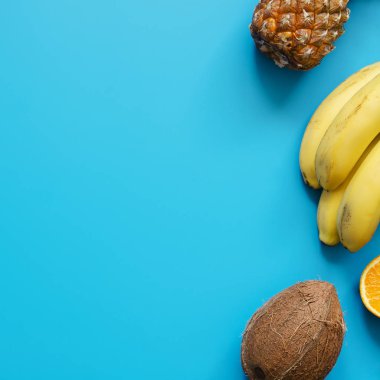 Tropikal meyve: muz, Hindistan cevizi, mavi arka plan üzerinde ananas. Yaz konsepti