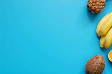 Tropikal meyve: muz, Hindistan cevizi, mavi arka plan üzerinde ananas. Yaz konsepti