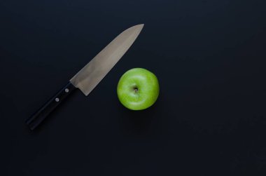 Yeşil elma ve siyah arka plan üzerinde bıçak. Havai çekim