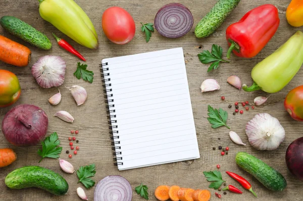 Frame of vegetables: cucumber, tomato, pepper, onion, garlic, parsley, carrot and notebook. Healthy food, Vegan or Harvest concept Copy space composition