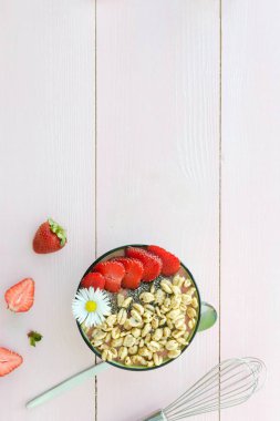 Pembe bir arka plan üzerinde hava buğday ve chia tohumu ile çilek güler yüzlü kase. Sağlıklı gıda. Temiz yemek. Kopyalama alanı kompozisyon