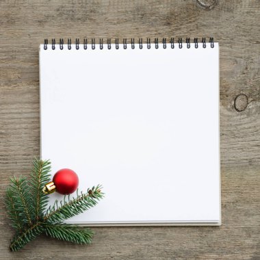Defter, çam dalları ve kırmızı Noel oyuncak eski ahşap masa üzerinde. Tatil kavramı. Kopyalama alanı kompozisyon