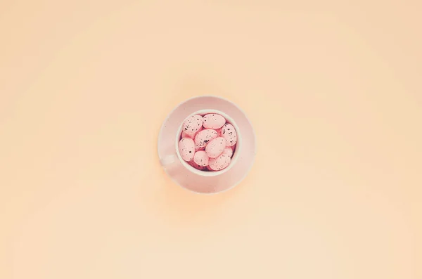 Pink easter eggs in coffee cup. Easter holiday background. Copy space composition. Retro toned
