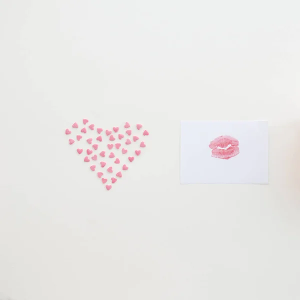 Kiss on paper and heart of small hearts on beige background. Pastel color. Congratulation concept. Flat lay style.