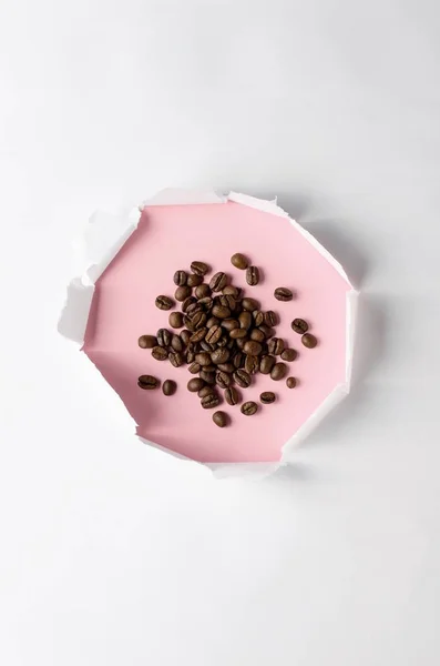 Paper hole in white paper and coffee beans on pink background. — Stock Photo, Image