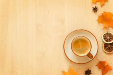 Bir fincan kahve ve sonbahar yaprakları ahşap arka planda.