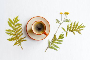 Beyaz ahşap arka planda kurumuş çiçekli kahve fincanı. Tepeden çekim