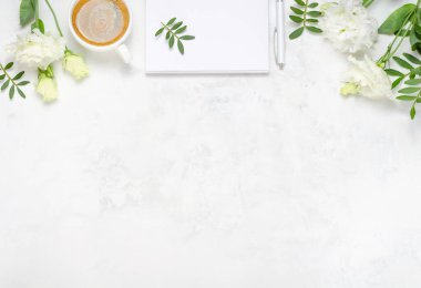 Bir fincan kahve, Eustoma, fıstıklı yeşillik, not defteri ve çimento kaplı kalem. Üst kattaki daire tepemizde duruyordu. Boşluk arkaplanı kopyala