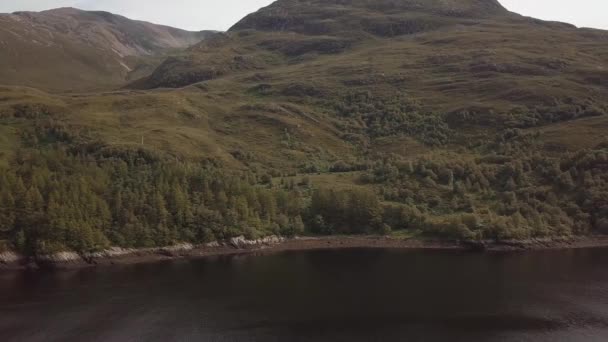 Luftaufnahme eines schottischen Sees mit von Bäumen und Vegetation bedeckten Bergen. schöner und sonniger Tag — Stockvideo