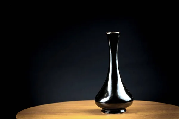 Minimalistic black vase on wooden table