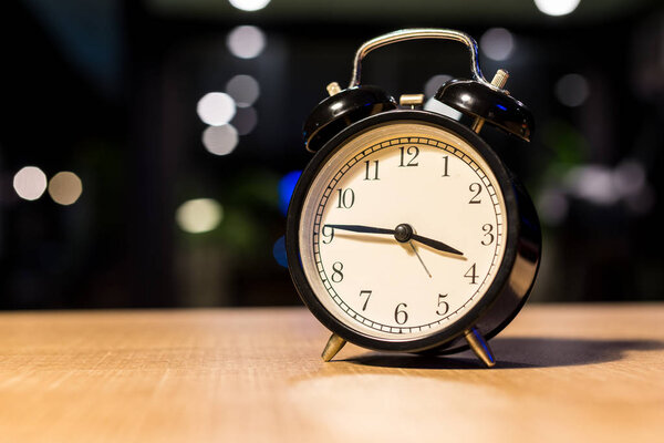 Black vintage alarm clock on blurry background 