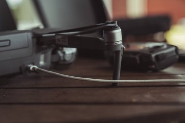 Eski ahşap masada bir uçuş kontrolörü ve dizüstü bilgisayar ile Drone quadcopter.