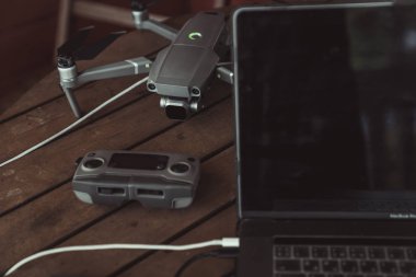 Eski ahşap masada bir uçuş kontrolörü ve dizüstü bilgisayar ile Drone quadcopter.