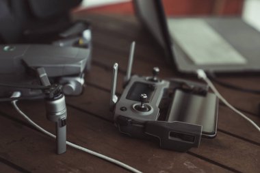 Eski ahşap masada bir uçuş kontrolörü ve dizüstü bilgisayar ile Drone quadcopter.