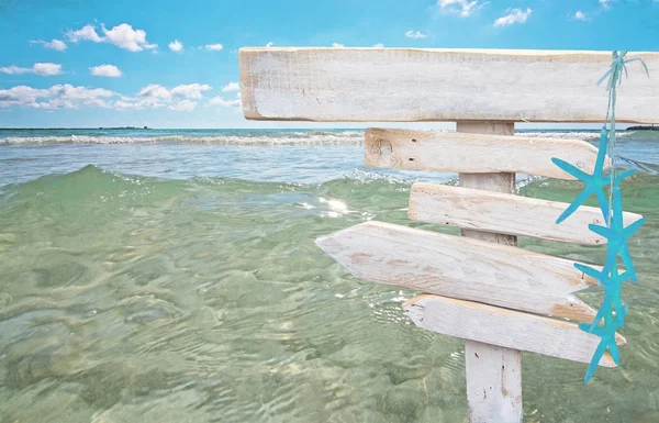 Rustic white empty wood signs with turquoise starfish over fresh green ocean water at Es Trenc, Mallorca