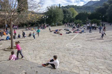 LLUC, MALLORCA, SPAIN - DECEMBER 3, 2018: School children playing in the yard on a day out to the monastery on a sunny day on December 3, 2018 in Lluc, Mallorca, Spain. clipart