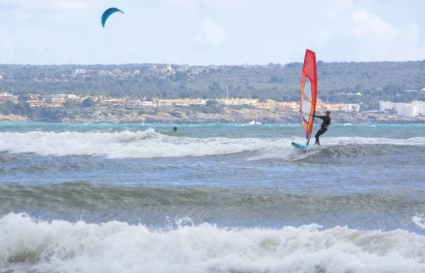 Windsurfer with red sail plays in the green waves — Stock Photo, Image