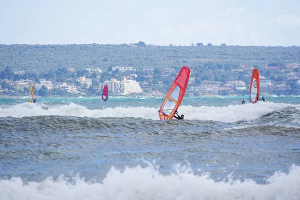 Windsurfer met rode zeil spelen in de groene golven — Stockfoto