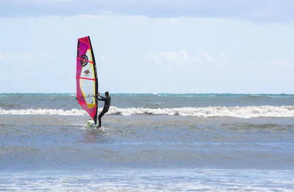 Windsurfer z czerwonym żagiel odgrywa w zielonych fal — Zdjęcie stockowe