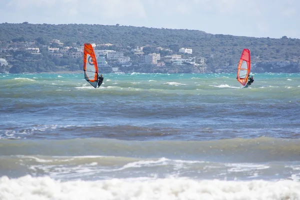 Dois windsurfistas com velas vermelhas em ondas verdes — Fotografia de Stock