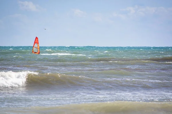 Windsurfer with red sail plays in the green waves — Stock Photo, Image