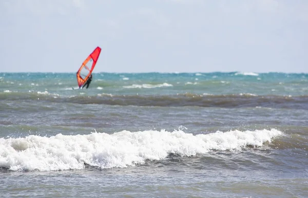 Windsurfer with red sail plays in the green waves — Stock Photo, Image