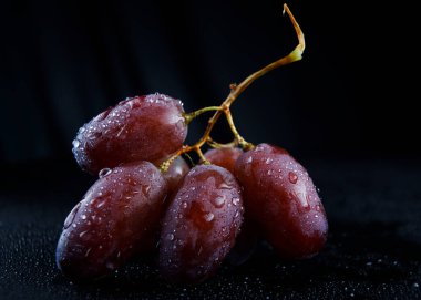 Bir demet üzüme bir damla su. Üzümler siyah bir arkaplanda izole edilir.