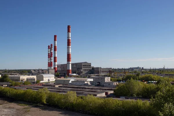 sanayi görünümü, borular, garajlar, fabrika binaları, parlak bir açık mavi gökyüzü ile sıcak bir gün